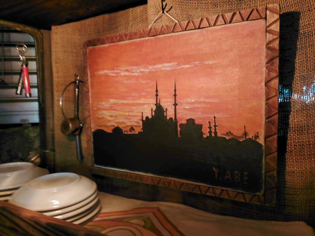 『カフェ アラジン』に飾られる阿部 弥四郎さん作のイスタンブールの夕陽の油絵